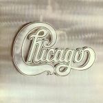 Auf einem polierten Edelstahl-Hintergrund ist der Schriftzug der geschwungene Schriftzug der Band Chicago in ebenfalls polierter Edelstahl-Optik zu sehen.